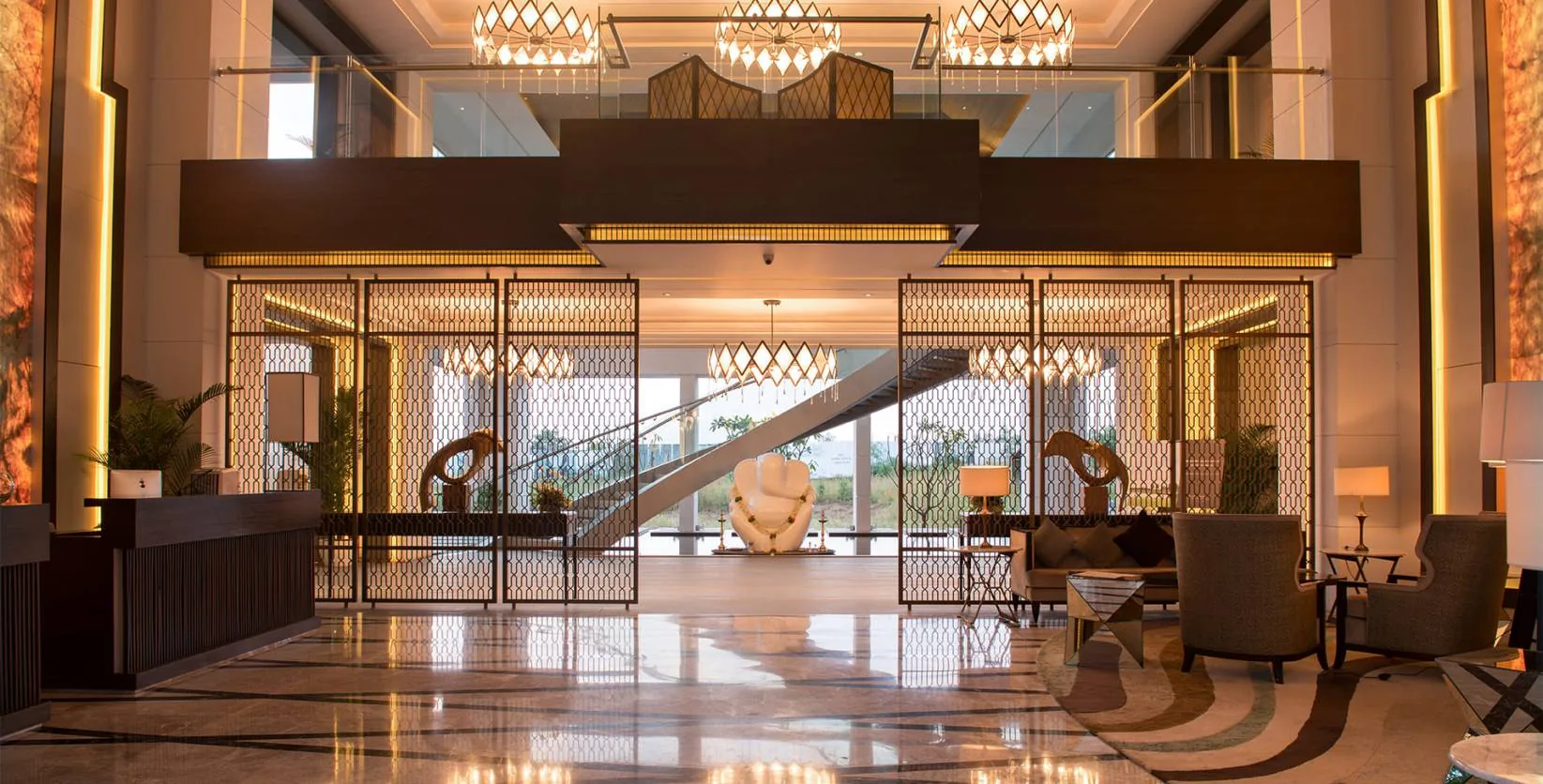 Double-height lobby with a mirrored ceiling and glass staircase executed by JRT