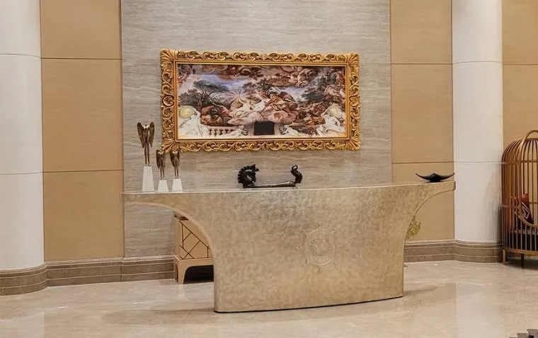 Sculpted reception desk set against a stone wall with a framed artwork